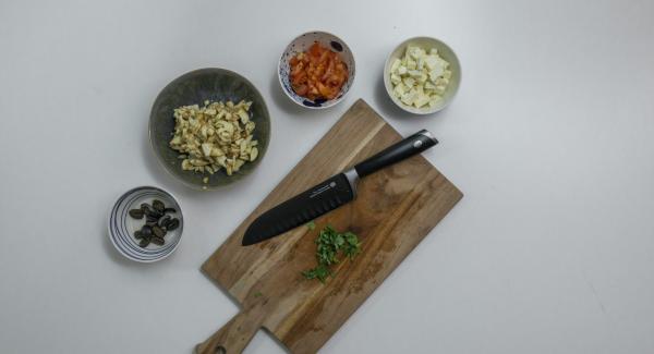 Tagliare il ripieno precedentemente conservato a pezzetti e cospargerlo di succo di limone. Pulire e tagliare a dadini il pomodoro. Tagliare nello stesso modo anche la feta e le olive. Tritare il tutto insieme alle foglie di basilico.