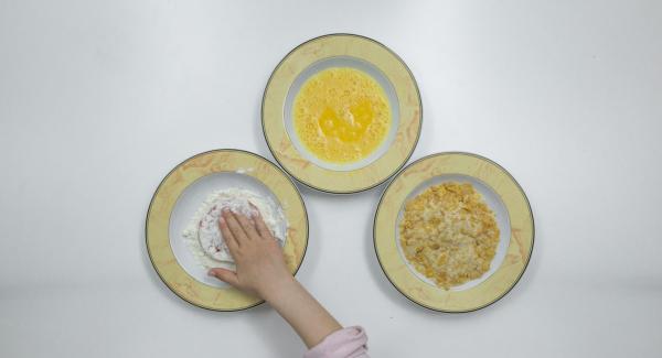 Passare le fette di pomodoro dapprima nella farina, poi nelle uova e, infine, nel miscuglio di pangrattato e cornflakes.