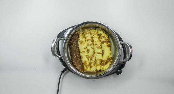 Posizionare l'Unità di cottura 24 cm 3,5 l su Navigenio ancora caldo. Versarvi metà della salsa al formaggio e disporvi sopra le crêpes farcite. Mescolare le carote rimaste con il resto della salsa e distribuire il composto sulle crêpes.