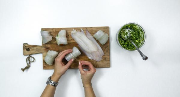 Spalmare un po’ di pesto sui filetti di pesce, disporre un pomodorino su ciascun filetto, arrotolarlo e fissarlo con uno stuzzicadenti.