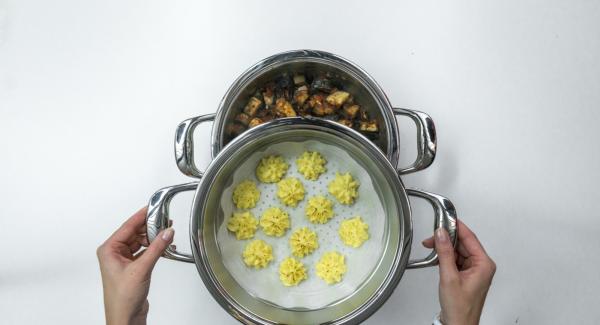 Guarnire lo stufato di melanzane con il basilico e servirlo con le patate duchessa.