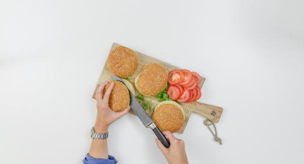 Tagliare a metà i panini, lavare la rucola e tagliare i pomodori a fette.