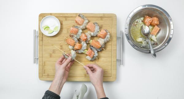 Sgocciolare i dadini di salmone e i gamberetti, infilarli su quattro spiedini, alternandoli, e aggiungendo due quarti di lime su ciascuno.