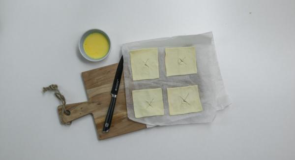 Incidere leggermente il quadrato di pasta sfoglia al centro facendo una croce o disegnando una piccola decorazione (es. cuore o stella) e spennellarla con il tuorlo d’uovo e il latte.