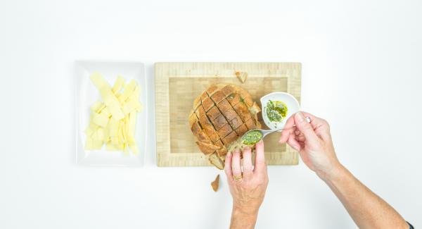 Irrorare gli intagli del pane con l’olio aromatizzato e riempirli con il formaggio tagliato a strisce.