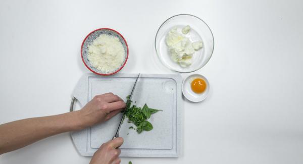 Tritare finemente le foglie di basilico e mescolarle con la ricotta o il formaggio fresco, il parmigiano e il tuorlo d’uovo.