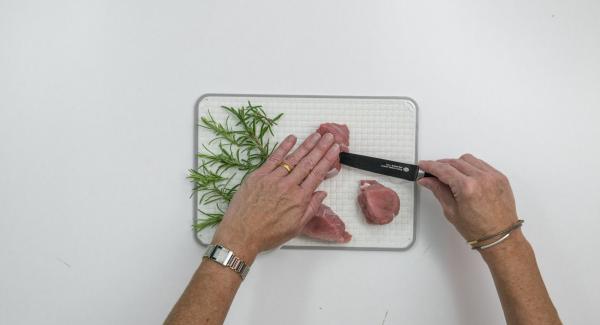 Pelare l’aglio e tagliarlo formando 12 striscioline. Dividere il rosmarino in 12 pezzetti. Tagliare in obliquo i medaglioni di maiale con un coltello sottile e affilato e inserire al loro interno un rametto di rosmarino e un pezzetto d’aglio.