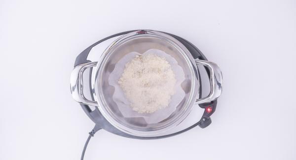 Al suono di Audiotherm, abbassare Navigenio a livello 2, adagiare un disco di carta da forno all'interno dell'Unità e posizionare al centro del disco 2-3 cucchiai di parmigiano grattugiato. Aiutandosi con un cucchiaio, stendere il formaggio uniformemente sul disco formando un cerchio e farlo sciogliere senza coperchio.