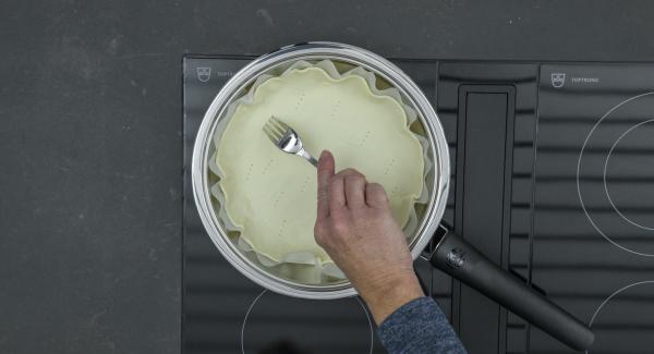 Adagiare la base di pasta sfoglia insieme con la carta forno nella Padella e bucherellarla con una forchetta. Regolare il fornello al massimo, coprire con Navigenio rivolto verso il basso impostato a livello II. Mentre la spia di Navigenio lampeggia di rosso/blu, impostare un tempo di cottura di ca. 3 minuti su Audiotherm(ca. 2 minuti se a induzione) e precuocere.