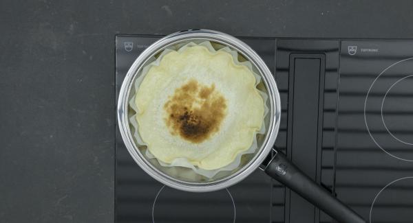 Spegnere il fornello (lasciare il fornello a induzione a ca. 100 Watt), distribuire le mandorle sulla pasta, poi le mele a fettine e, infine, versare la crema. Riposizionare Navigenio e impostarlo a livello II. Mentre la spia di Navigenio lampeggia di rosso/blu, impostare un tempo di ca. 2 minuti su Audiotherm. Cuocere la crostata di mele finché la superficie diventa dorata.