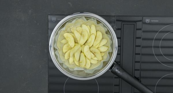 Spegnere il fornello (lasciare il fornello a induzione a ca. 100 Watt), distribuire le mandorle sulla pasta, poi le mele a fettine e, infine, versare la crema. Riposizionare Navigenio e impostarlo a livello II. Mentre la spia di Navigenio lampeggia di rosso/blu, impostare un tempo di ca. 2 minuti su Audiotherm. Cuocere la crostata di mele finché la superficie diventa dorata.