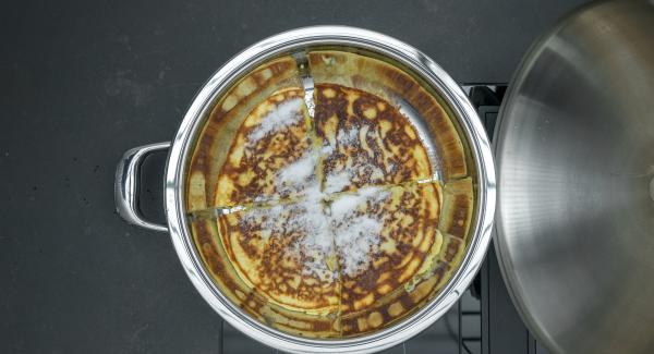 Togliere il coperchio, cospargere il dolce di zucchero, tagliarlo a pezzettini, scuotere per far caramellare il tutto fino a ottenere una doratura uniforme.