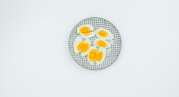 Lavare e pulire bene l'insalata. Tagliare le uova sode in otto parti.