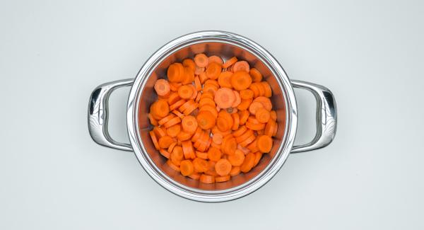 Pelare le carote, tagliarle a rondelle e metterle bagnate d'acqua nell'Unità di cottura 20 cm.