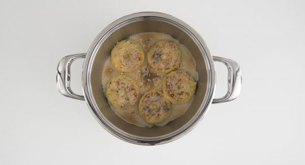 Al suono di Audiotherm, sollevare Navigenio e spolverare le ciambelle con il parmigiano rimasto. Coprire nuovamente l'Unità con Navigenio impostato a livello II. Mentre la spia lampeggia, inserire un tempo di 1 minuti su Audiotherm e gratinare fino a ottenere la croccantezza desiderata.