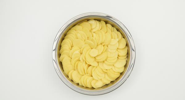 Pelare le patate, affettarle sottilmente e trasferirle in NonSoloForno. Versarvi sopra il composto di panna e latte e coprire con il coperchio.