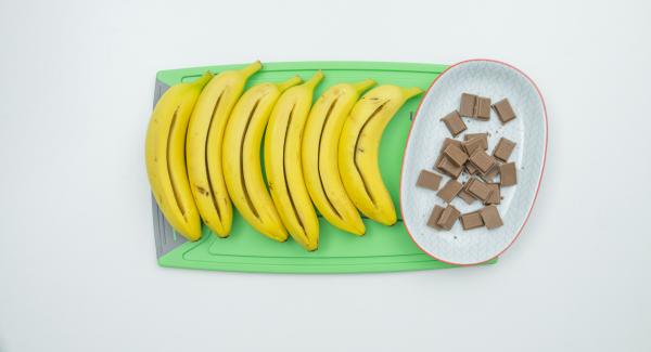 Lavare accuratamente le banane con la buccia e asciugarle. Con un coltello inciderle per il lungo (non tagliarle completamente), aprire leggermente l’apertura con le dita e riempirla con i pezzetti di cioccolato (il cioccolato non deve sporgere al di fuori dell’apertura, altrimenti fuoriesce durante la preparazione).