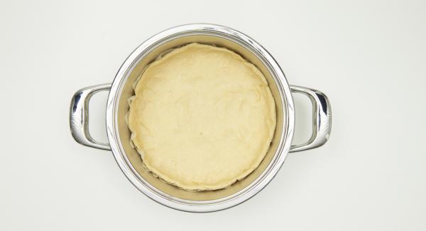 Disporre la carta da forno nell’unità di cottura e ungere leggermente il bordo inferiore dell’unità di cottura. Stendere la pasta lievitata in un disco di circa 26 cm di diametro e disporlo sopra la carta da forno, in modo da creare un piccolo bordo. Versarvi sopra il ripieno di cipolle e il composto di uovo, quindi cospargere con il cumino.