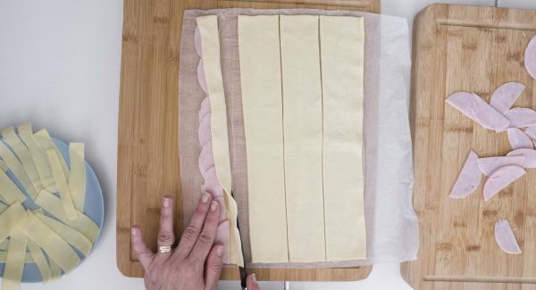 Piegare a metà la pasta sfoglia, lasciando il prosciutto e il formaggio al centro e arrotolare.