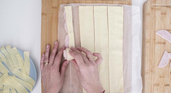 Piegare a metà la pasta sfoglia, lasciando il prosciutto e il formaggio al centro e arrotolare.