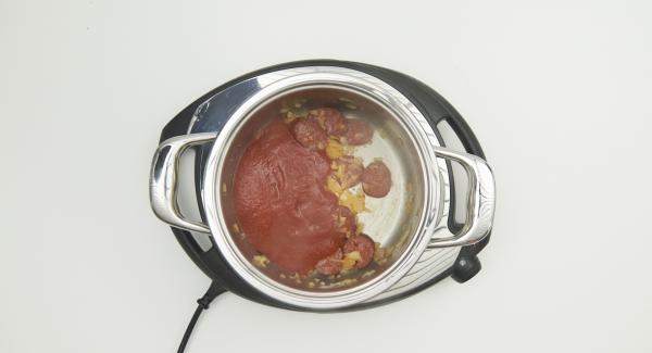 Al suono di Audiotherm, abbassare Navigenio a livello 2, mescolare e rosolare il misto di cipolla e aglio e aggiungere le fette di chorizo. Aggiungere la paprika, la passata di pomodoro, l’acqua, la pasta e la foglia di alloro. Mescolare bene il tutto.