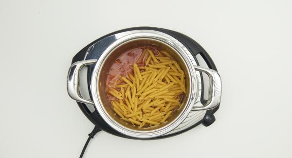 Al suono di Audiotherm, abbassare Navigenio a livello 2, mescolare e rosolare il misto di cipolla e aglio e aggiungere le fette di chorizo. Aggiungere la paprika, la passata di pomodoro, l’acqua, la pasta e la foglia di alloro. Mescolare bene il tutto.