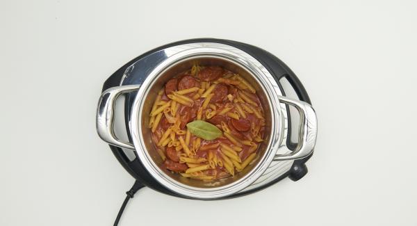 Al suono di Audiotherm, abbassare Navigenio a livello 2, mescolare e rosolare il misto di cipolla e aglio e aggiungere le fette di chorizo. Aggiungere la paprika, la passata di pomodoro, l’acqua, la pasta e la foglia di alloro. Mescolare bene il tutto.