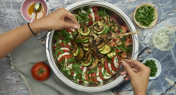 Prima di servire, tritare le foglie di basilico e distribuirle sui pomodori e sulla mozzarella.