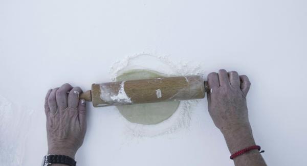 Dividere la pasta in due. Spolverizzare il piano di lavoro con la farina, stendere metà della pasta in modo che fuoriesca dal bordo dell’unità di cottura per ca. 1 cm. Disporla nell’unità di cottura con carta da forno.