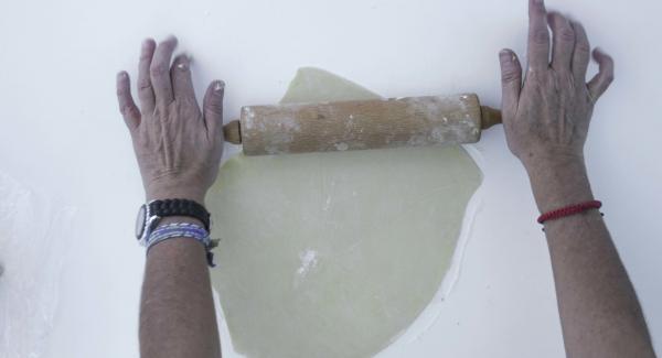 Dividere la pasta in due. Spolverizzare il piano di lavoro con la farina, stendere metà della pasta in modo che fuoriesca dal bordo dell’unità di cottura per ca. 1 cm. Disporla nell’unità di cottura con carta da forno.