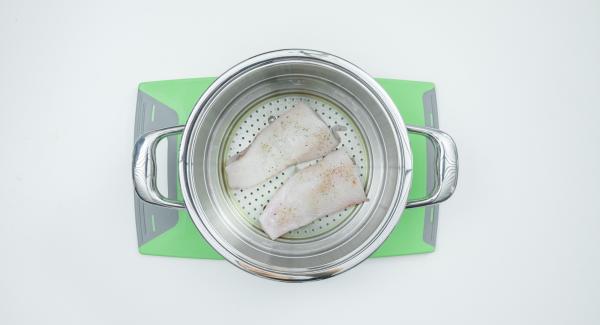 Tagliare a metà il filetto di pesce, insaporirlo con sale e pepe e adagiarlo nell’inserto "2 in 1". Lavare il limone, tagliarlo a fette e disporle sopra il pesce.