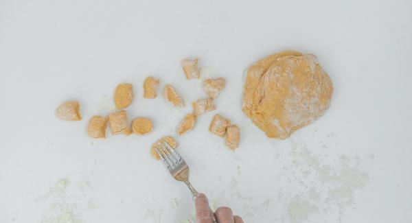 Sulla spianatoia infarinata, dividere la pasta in rotolini, tagliarli a pezzetti e passarli su una forchetta per dargli la tipica forma degli gnocchi.