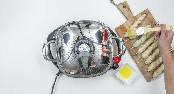 Spennellare con un filo d’olio i 4 spiedini su ogni lato. Al suono di Audiotherm, abbassare Navigenio a livello 2 e inserire gli spiedini all'interno dell'Unità. Coprire nuovamente con il coperchio e proseguire la cottura per ca. 4 minuti. Spennellare con un filo d’olio i 4 spiedini su ogni lato. Al suono di Audiotherm, abbassare Navigenio a livello 2 e inserire gli spiedini all'interno dell'Unità. Coprire nuovamente con il coperchio e proseguire la cottura per ca. 4 minuti.
