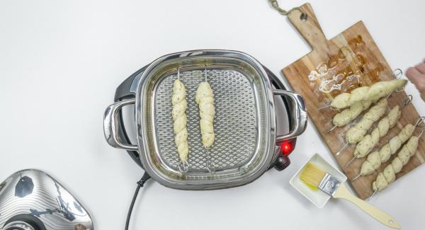 Spennellare con un filo d’olio i 4 spiedini su ogni lato. Al suono di Audiotherm, abbassare Navigenio a livello 2 e inserire gli spiedini all'interno dell'Unità. Coprire nuovamente con il coperchio e proseguire la cottura per ca. 4 minuti. Spennellare con un filo d’olio i 4 spiedini su ogni lato. Al suono di Audiotherm, abbassare Navigenio a livello 2 e inserire gli spiedini all'interno dell'Unità. Coprire nuovamente con il coperchio e proseguire la cottura per ca. 4 minuti.