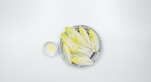 Lavare la cicoria, tagliarla a metà per il lungo ed eliminare la parte amara centrale. Sgocciolare leggermente e adagiare all'interno dell’Unità di cottura 24 cm 3,5 l e bagnare con succo di limone.