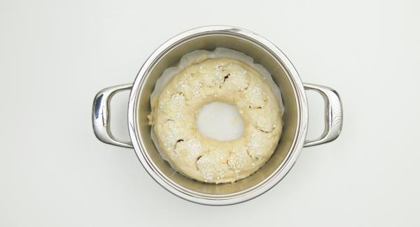 Arrotolare la pasta dal lato più lungo, formare una corona e posizionarla sulla carta da forno, nell’unità di cottura. Incidere la superficie della corona con delle forbici, spennellarla con il latte e cospargerla con la granella di zucchero e le mandorle a lamelle.