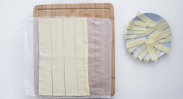 Stendere la pasta sfoglia e tagliarla in 5 strisce. Mettere il formaggio su metà della pasta sfoglia e poi le fette di prosciutto, lasciandole sporgere un po'.