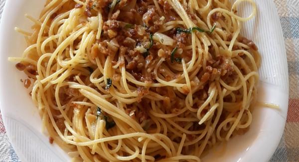 Togliete lo spicchio d'aglio e aggiungete un pò di acqua di cottura .
Quando gli spaghetti saranno cotti al dente , scolate e versateli nella   padella .
Mantecate tutto con origano, prezzemolo e infine il pangrattato di crackers.